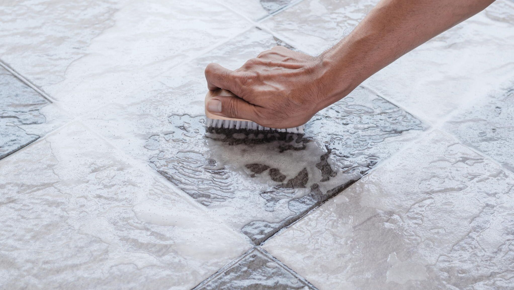 Worker scrubbing tile and grout